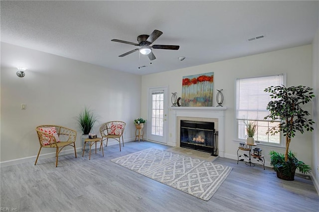 unfurnished room featuring ceiling fan, a healthy amount of sunlight, a fireplace, and light hardwood / wood-style floors