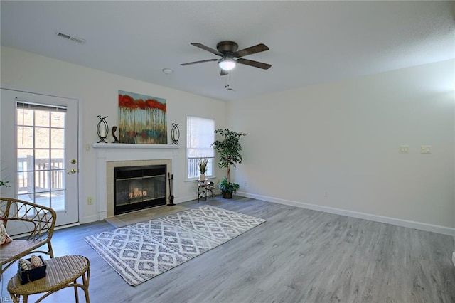 unfurnished living room featuring hardwood / wood-style floors, a tile fireplace, a wealth of natural light, and ceiling fan