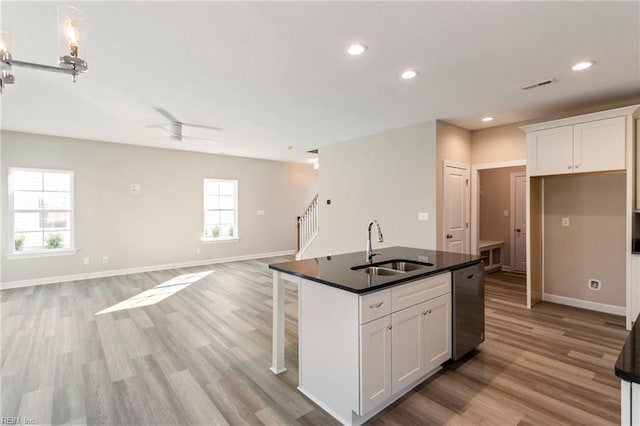 kitchen with white cabinetry, stainless steel dishwasher, sink, and a center island with sink