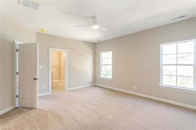 spare room with ceiling fan, plenty of natural light, and light carpet