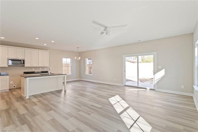 kitchen featuring sink, white cabinetry, decorative light fixtures, light hardwood / wood-style flooring, and ceiling fan with notable chandelier