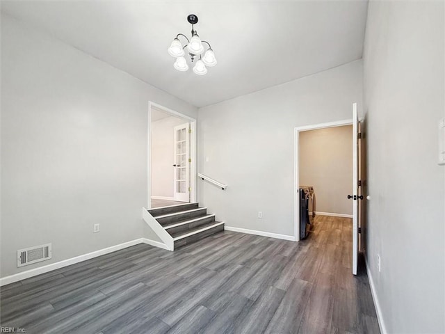 spare room with dark hardwood / wood-style flooring and a notable chandelier