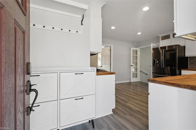 kitchen featuring wooden counters, stainless steel fridge, white cabinets, hardwood / wood-style floors, and backsplash