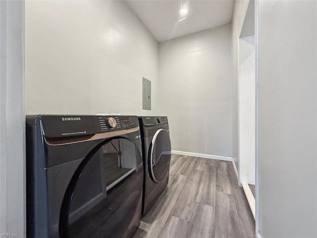 washroom with wood-type flooring, electric panel, and washer and dryer