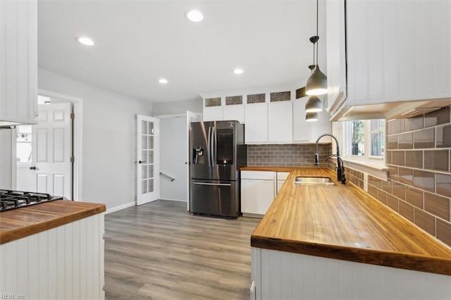 kitchen with sink, butcher block countertops, white cabinetry, decorative light fixtures, and appliances with stainless steel finishes