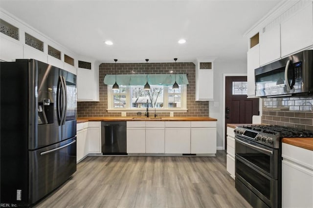 kitchen featuring wood counters, a healthy amount of sunlight, white cabinets, and appliances with stainless steel finishes