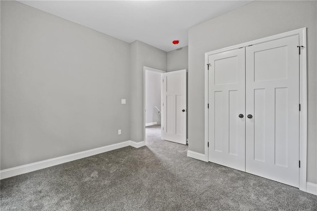 unfurnished bedroom with a closet and dark colored carpet