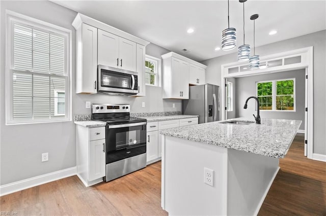 kitchen with sink, white cabinetry, an island with sink, pendant lighting, and stainless steel appliances