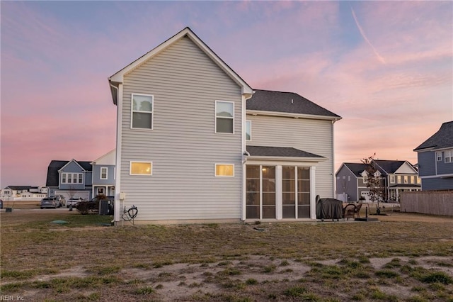 back house at dusk with a sunroom