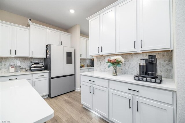 kitchen with stainless steel refrigerator, white cabinetry, tasteful backsplash, and light hardwood / wood-style flooring