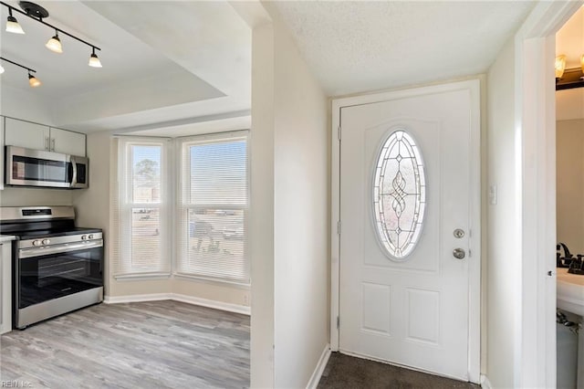 foyer entrance featuring track lighting, a textured ceiling, and light wood-type flooring