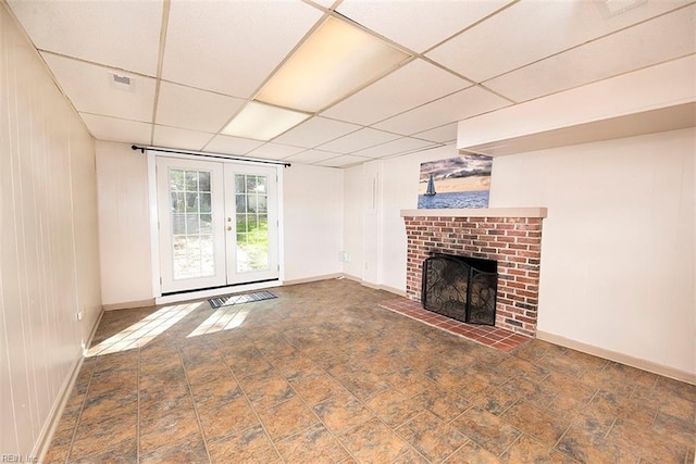 unfurnished living room with a brick fireplace, a paneled ceiling, and french doors