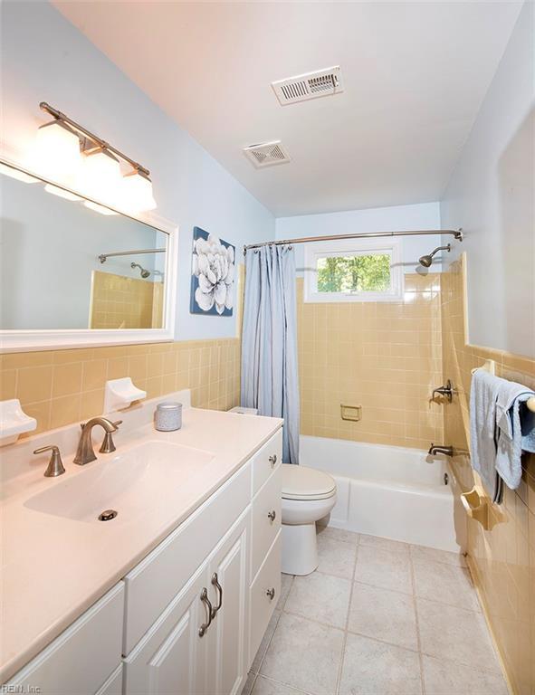 full bathroom featuring tile walls, vanity, toilet, shower / bathtub combination with curtain, and tile patterned floors