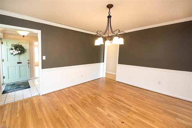 unfurnished dining area with ornamental molding, a notable chandelier, and light hardwood / wood-style flooring