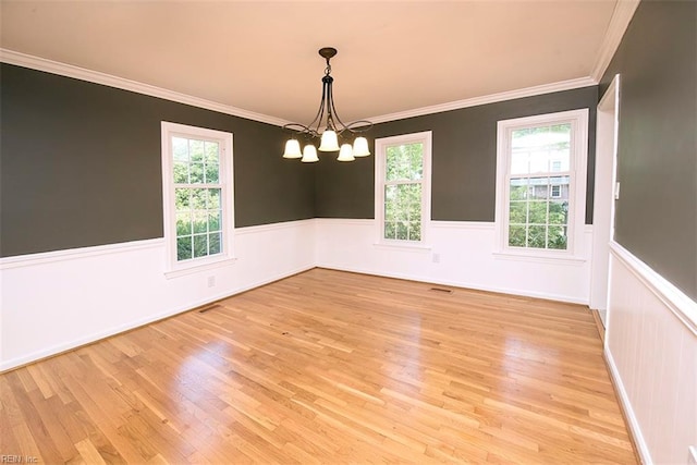 unfurnished room with crown molding, light hardwood / wood-style flooring, and a notable chandelier