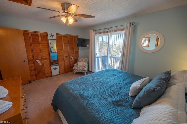 carpeted bedroom with multiple closets, ceiling fan, and a textured ceiling