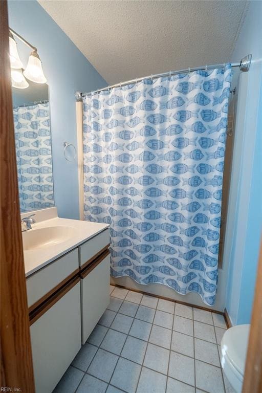 full bathroom featuring vanity, tile patterned floors, toilet, and a textured ceiling