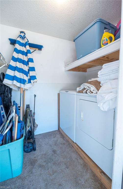 laundry room with dark carpet, washer and dryer, and a textured ceiling