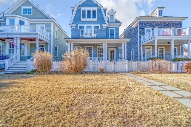 view of front of house featuring a balcony, covered porch, and a front lawn