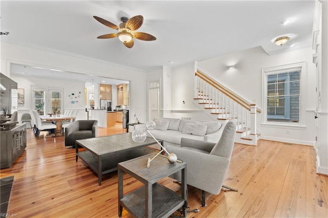 living room with ornamental molding, light hardwood / wood-style floors, and ceiling fan