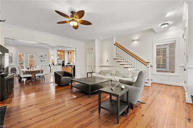 living room featuring ceiling fan, ornamental molding, and light hardwood / wood-style flooring