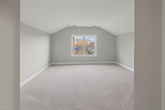 bonus room with lofted ceiling and light carpet