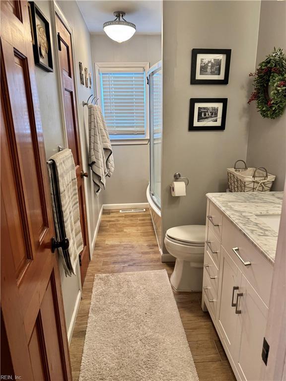 bathroom featuring hardwood / wood-style flooring, vanity, toilet, and a shower with shower door