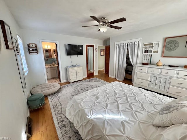 bedroom featuring ceiling fan, a closet, light hardwood / wood-style floors, and ensuite bath