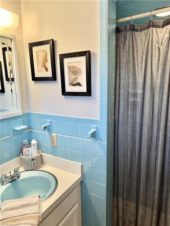 bathroom with tile walls, vanity, and walk in shower