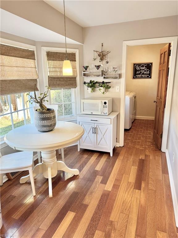 dining room featuring dark wood-type flooring, separate washer and dryer, and breakfast area