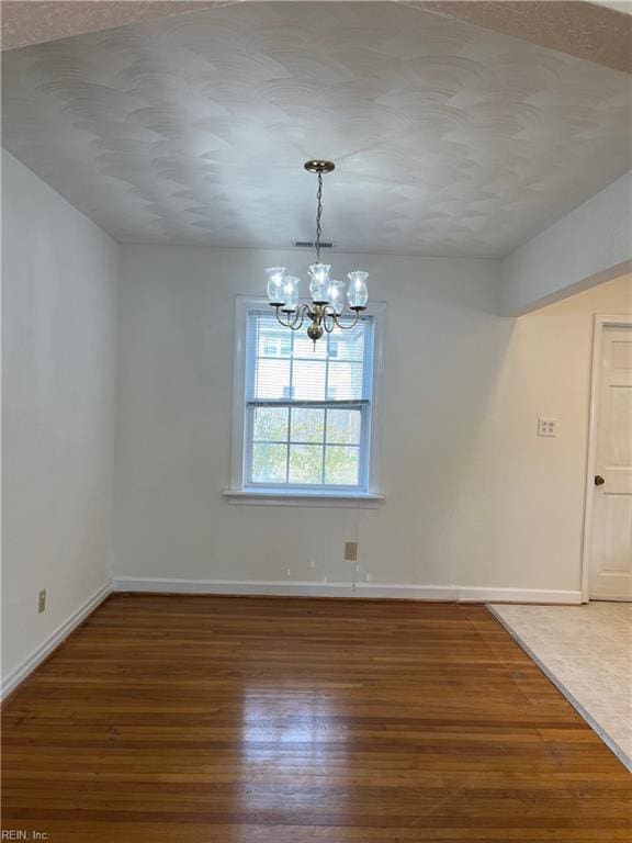 unfurnished dining area with an inviting chandelier and dark hardwood / wood-style flooring