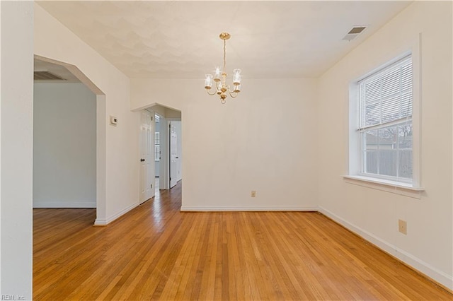 empty room featuring light hardwood / wood-style floors and a notable chandelier