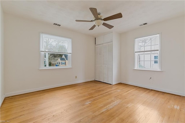 unfurnished bedroom with ceiling fan, a closet, light hardwood / wood-style floors, and multiple windows