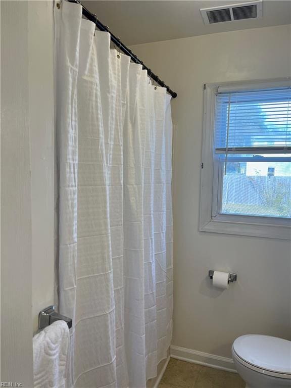 bathroom featuring a shower with shower curtain, tile patterned floors, and toilet