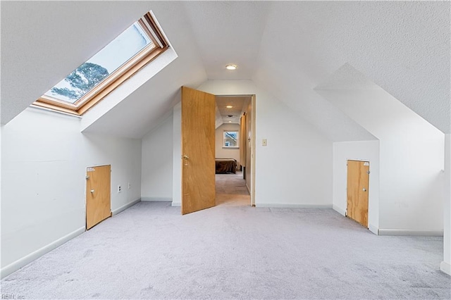 bonus room with lofted ceiling, a healthy amount of sunlight, light colored carpet, and a textured ceiling