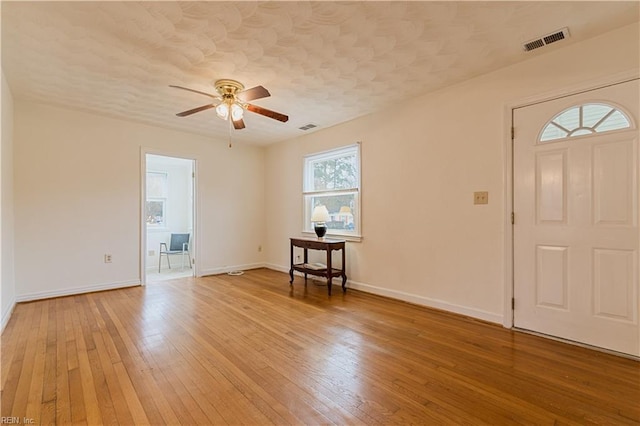 entryway with ceiling fan, wood-type flooring, and a textured ceiling