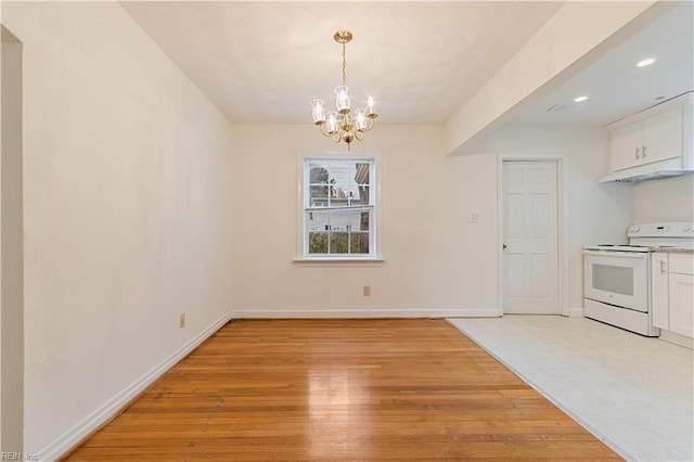 unfurnished dining area with an inviting chandelier and light hardwood / wood-style flooring