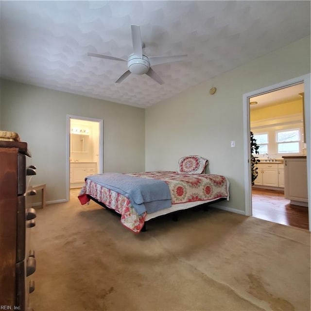 carpeted bedroom with ceiling fan, sink, and ensuite bath