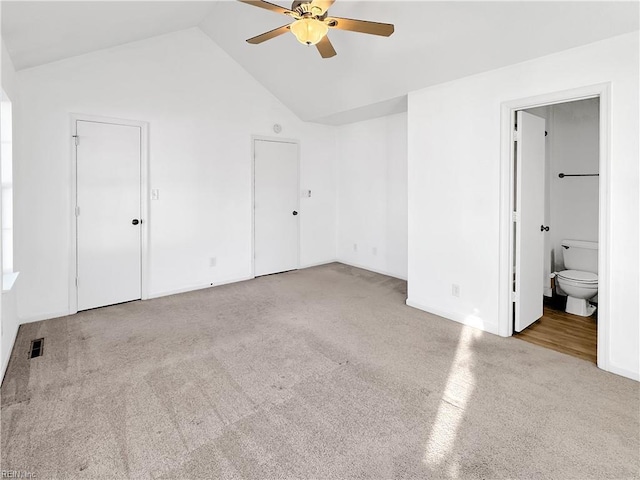 unfurnished bedroom with high vaulted ceiling, light colored carpet, ceiling fan, and ensuite bathroom