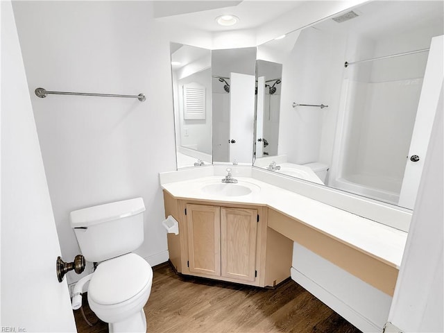 bathroom featuring wood-type flooring, toilet, vanity, and a shower