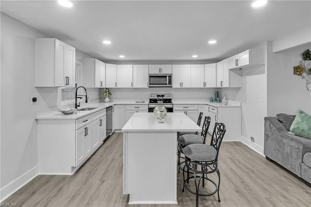 kitchen featuring white cabinetry, appliances with stainless steel finishes, a center island, and a breakfast bar area