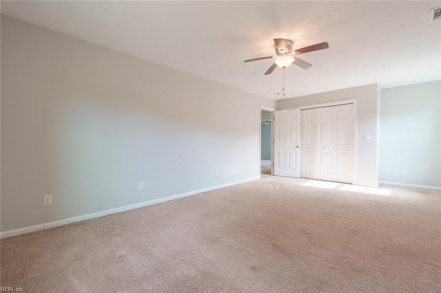 unfurnished bedroom featuring light colored carpet, ceiling fan, and a closet