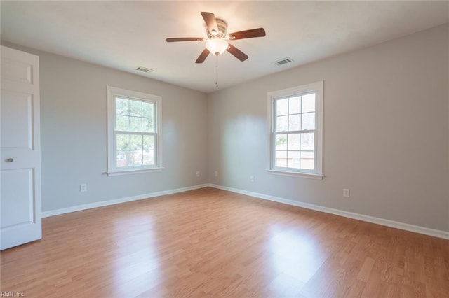 empty room featuring ceiling fan, plenty of natural light, and light hardwood / wood-style floors