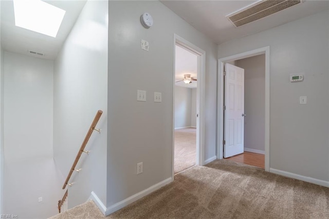 hallway with a skylight and light carpet