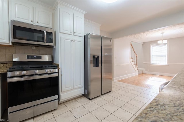 kitchen with appliances with stainless steel finishes, decorative light fixtures, tasteful backsplash, white cabinets, and light tile patterned floors