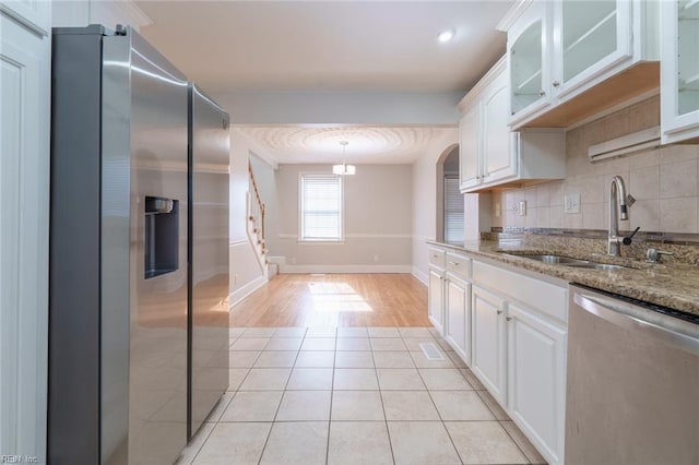 kitchen featuring appliances with stainless steel finishes, backsplash, white cabinets, and light stone counters