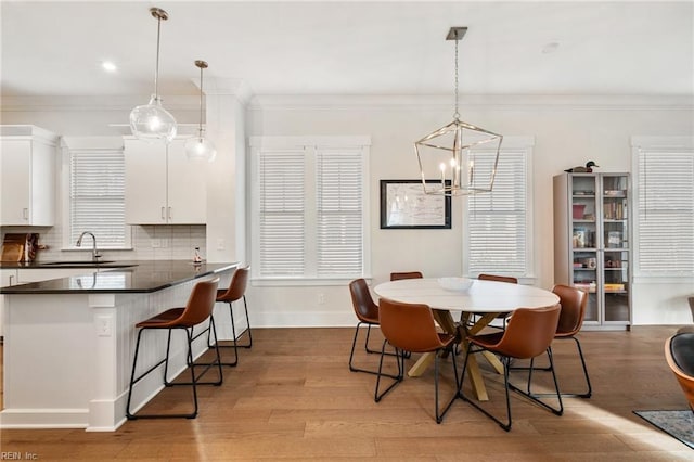 dining area with ornamental molding, sink, and light hardwood / wood-style floors