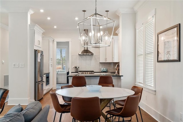 dining area featuring hardwood / wood-style flooring, ornamental molding, and sink