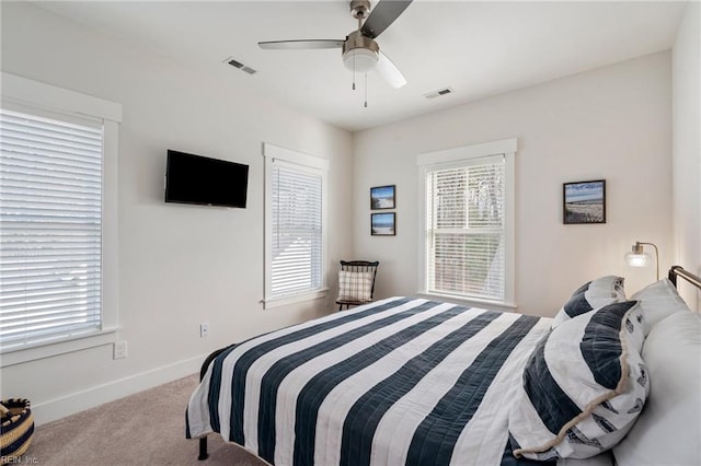 bedroom with ceiling fan, light colored carpet, and multiple windows