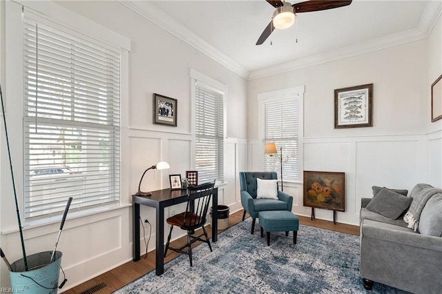 sitting room with wood-type flooring, ornamental molding, and ceiling fan